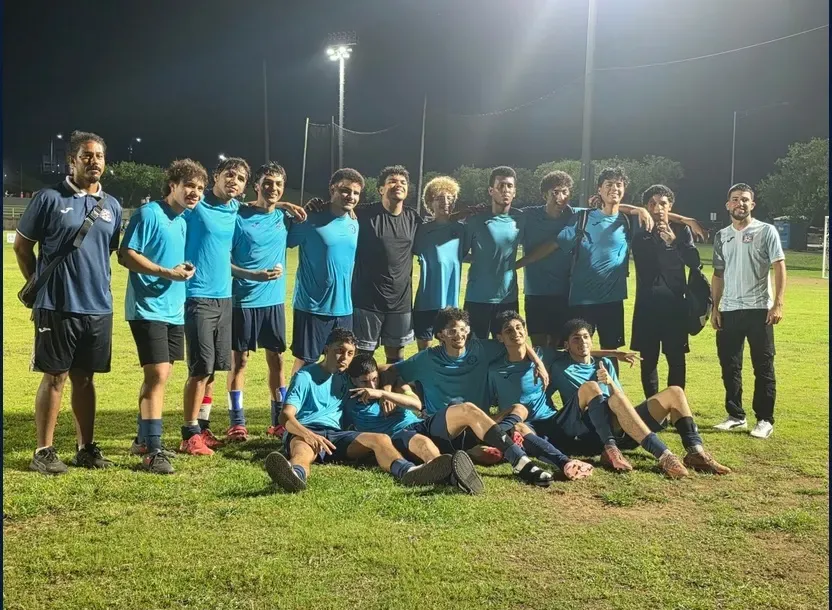 El equipo U20 de Ivy League SC posa junto a la portería tras su partido nocturno